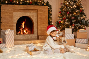 good-looking-female-child-playing-with-her-pekingese-dog-little-girl-wearing-white-sweater-santa-claus-hat-posing-festive-room-with-fireplace-xmas-tree